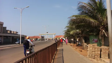 The road to the Ghana–Togo border at Aflao, with palm trees, street lights and the border arch in the distance